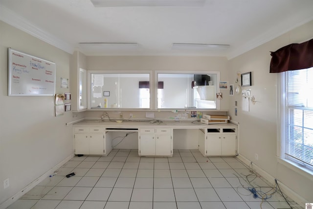 kitchen with light tile patterned floors, white cabinets, crown molding, and built in desk