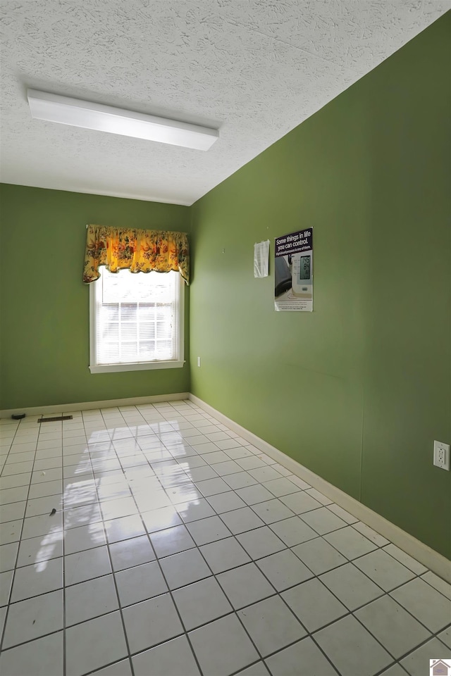 spare room featuring a textured ceiling and light tile patterned flooring