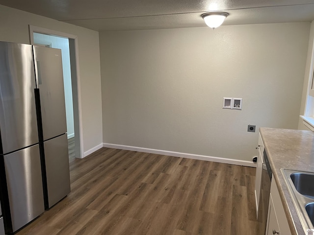 kitchen with sink, dark hardwood / wood-style flooring, stainless steel refrigerator, and white cabinetry