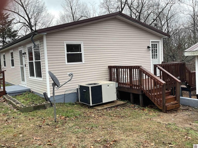 rear view of property with a deck, cooling unit, and a lawn