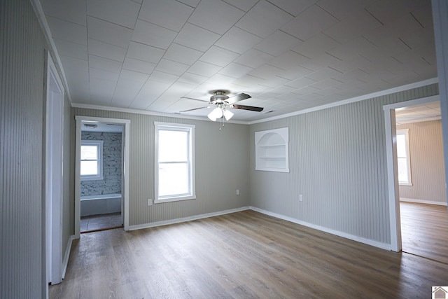 unfurnished room featuring a healthy amount of sunlight, built in features, and hardwood / wood-style flooring