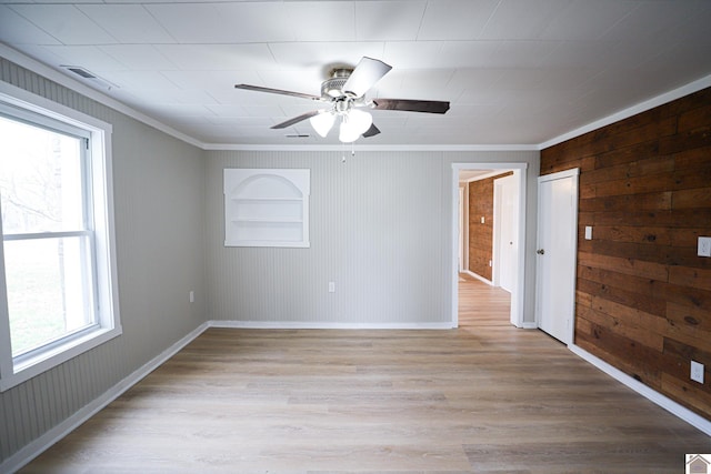 unfurnished room featuring plenty of natural light, built in shelves, light hardwood / wood-style flooring, and crown molding