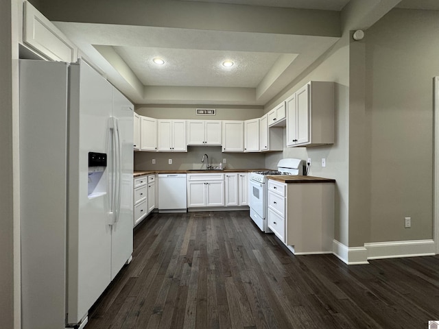 kitchen with a raised ceiling, white cabinets, sink, and white appliances