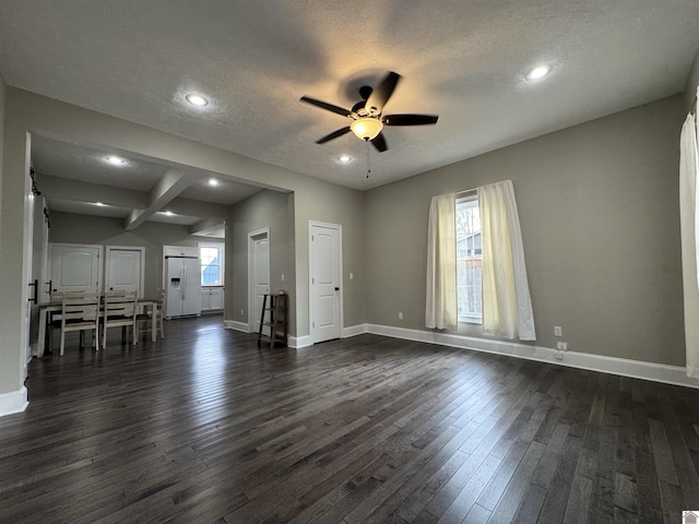 unfurnished living room featuring a textured ceiling, ceiling fan, plenty of natural light, and beamed ceiling