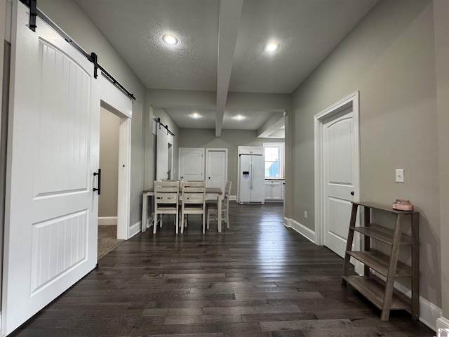 dining area featuring a textured ceiling, dark hardwood / wood-style flooring, and a barn door