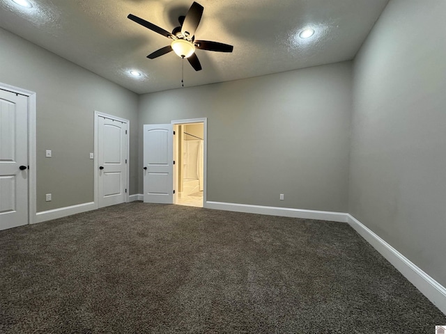 unfurnished bedroom featuring ceiling fan, a textured ceiling, connected bathroom, and dark colored carpet