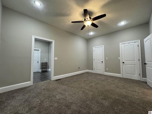 unfurnished bedroom featuring a textured ceiling, ceiling fan, and dark colored carpet