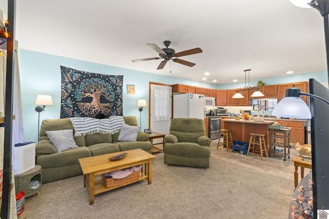 carpeted living room featuring ceiling fan and sink