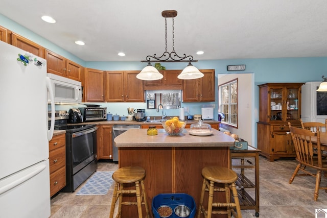 kitchen with a kitchen island, decorative light fixtures, stainless steel appliances, sink, and a breakfast bar area