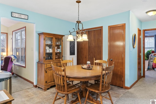 carpeted dining room featuring plenty of natural light and an inviting chandelier