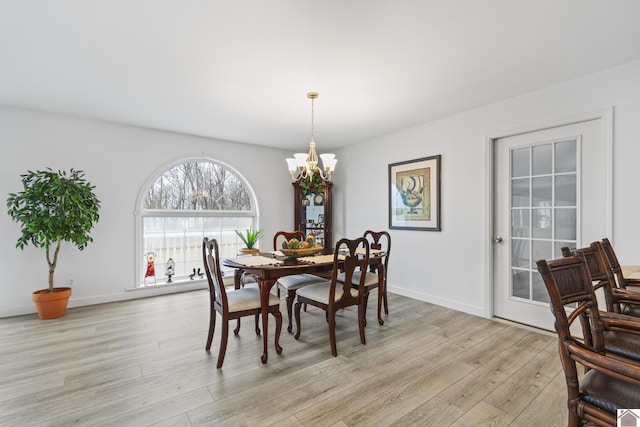 dining space with light wood-type flooring and a notable chandelier