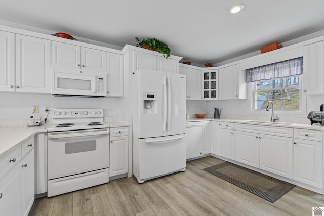 kitchen with light wood-type flooring, sink, white appliances, and white cabinetry