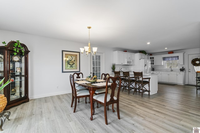 dining space featuring light wood-type flooring, sink, and a chandelier