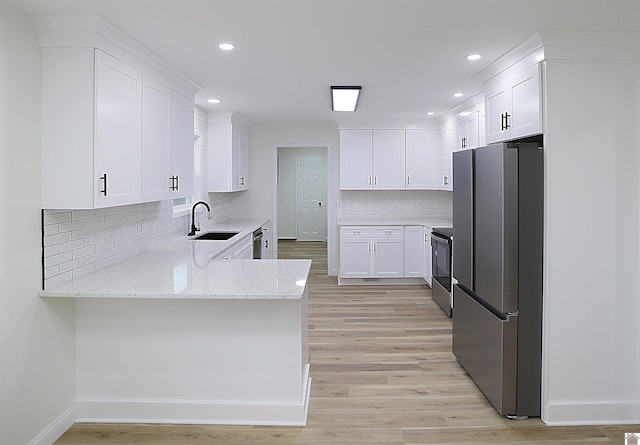 kitchen featuring white cabinets, appliances with stainless steel finishes, tasteful backsplash, sink, and light stone counters