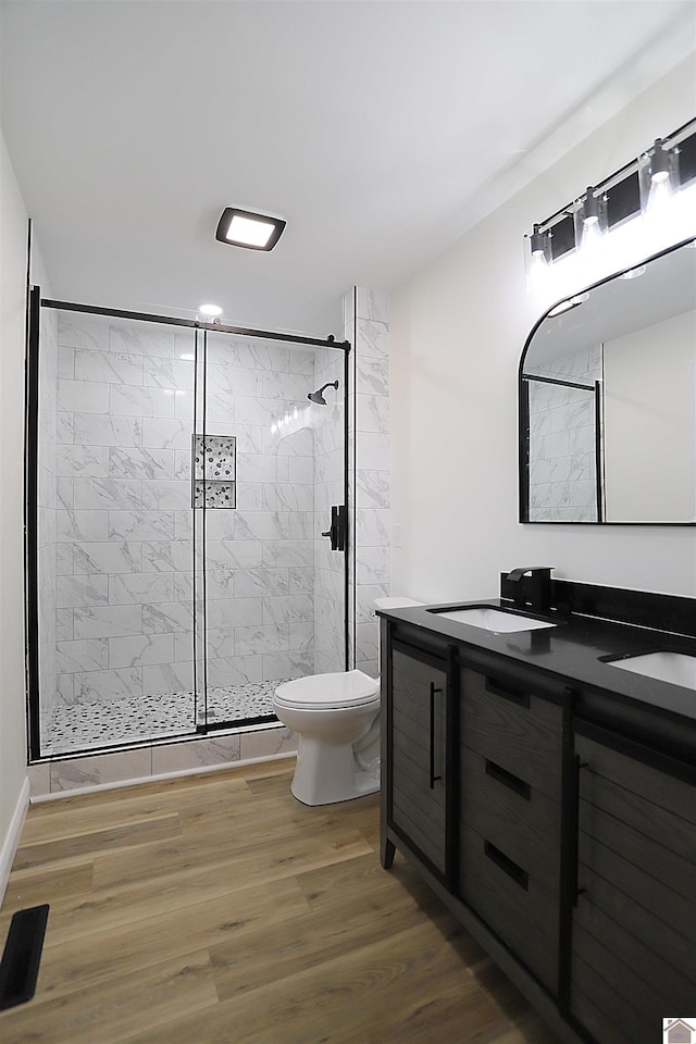 bathroom with wood-type flooring, walk in shower, vanity, and toilet