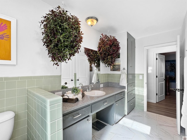 bathroom with tile walls, toilet, and vanity