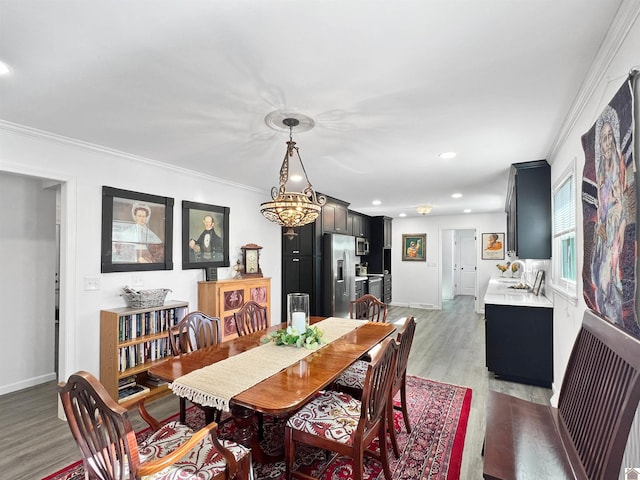 dining area with light hardwood / wood-style flooring, ornamental molding, and an inviting chandelier