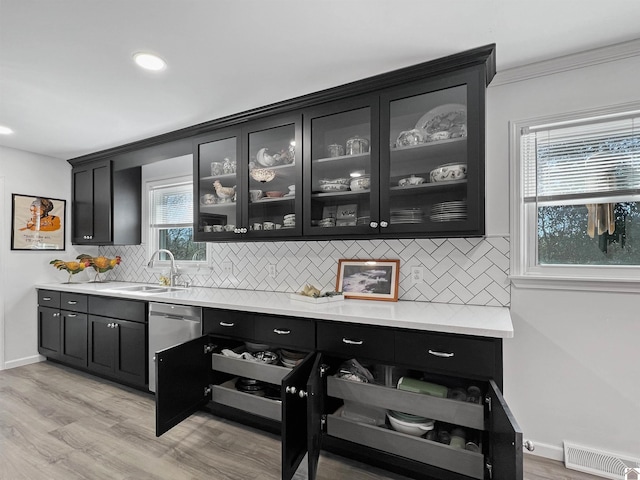 bar with tasteful backsplash, dishwasher, sink, and light hardwood / wood-style floors