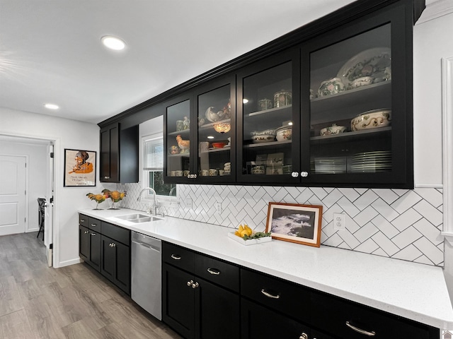 bar with sink, backsplash, dishwasher, and light hardwood / wood-style flooring