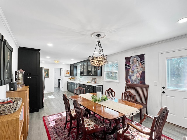 dining space featuring light hardwood / wood-style floors, a wealth of natural light, crown molding, and a notable chandelier