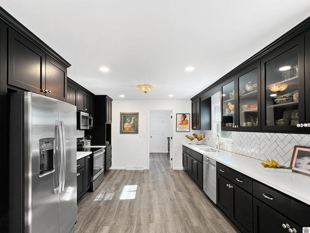 kitchen featuring tasteful backsplash, sink, stainless steel appliances, and light hardwood / wood-style floors