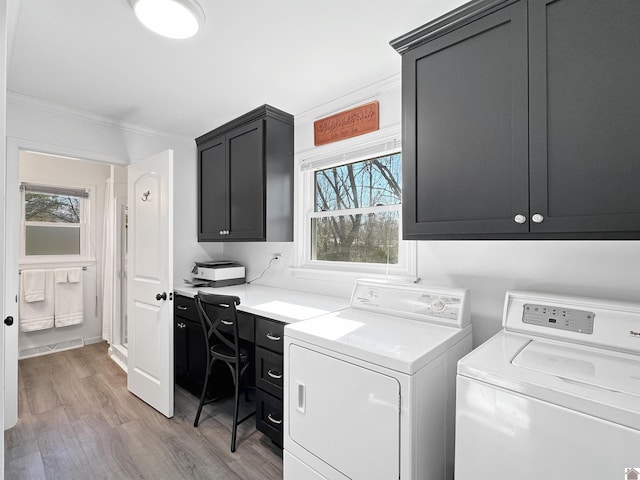 clothes washing area featuring cabinets, crown molding, hardwood / wood-style floors, and washing machine and clothes dryer