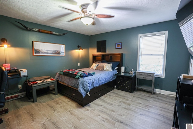 bedroom with ceiling fan, light hardwood / wood-style floors, and a textured ceiling