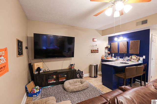 living room featuring ceiling fan, light tile patterned flooring, and a textured ceiling