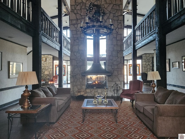 living room featuring a towering ceiling, an inviting chandelier, and a wood stove