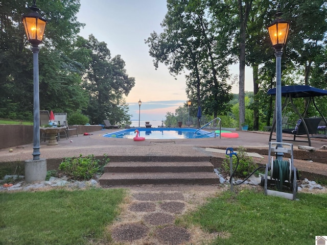 pool at dusk featuring a patio area