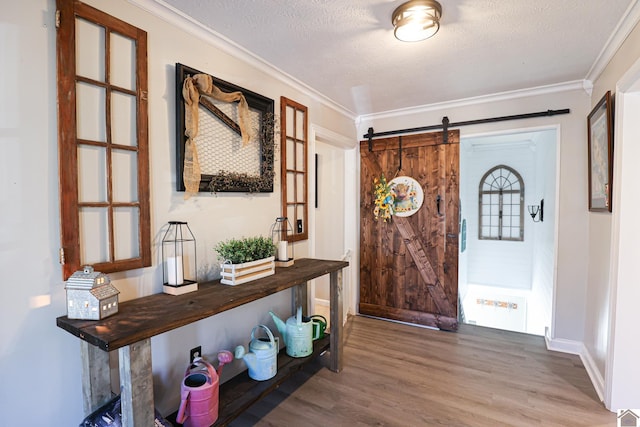 entryway with a textured ceiling, crown molding, a barn door, and hardwood / wood-style flooring