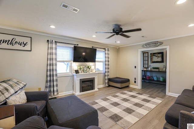 living room with ceiling fan, crown molding, and light hardwood / wood-style flooring