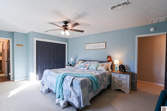 carpeted bedroom featuring ceiling fan, a textured ceiling, and a closet