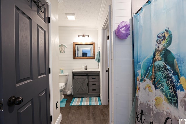 bathroom with a textured ceiling, hardwood / wood-style floors, vanity, toilet, and crown molding