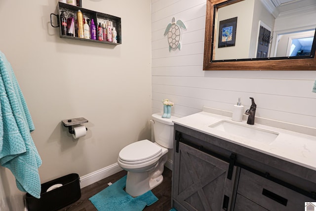 bathroom featuring toilet, hardwood / wood-style flooring, wooden walls, crown molding, and vanity