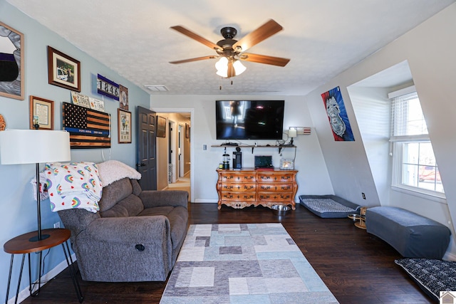 living room featuring ceiling fan, a textured ceiling, and dark hardwood / wood-style floors