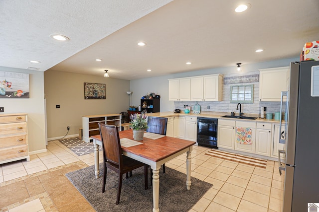 kitchen with dishwasher, sink, stainless steel refrigerator, white cabinetry, and light tile patterned floors