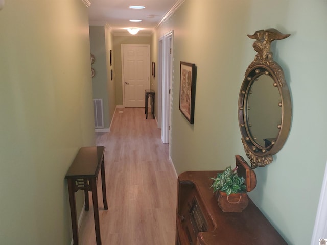 hallway with light wood-type flooring and crown molding