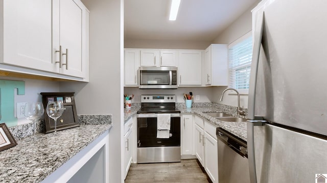 kitchen featuring white cabinets, appliances with stainless steel finishes, sink, and light stone counters