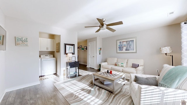 living room featuring ceiling fan, independent washer and dryer, and light wood-type flooring