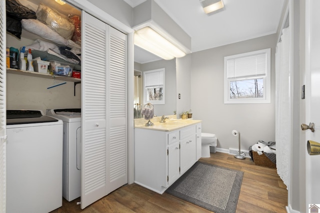 bathroom with hardwood / wood-style flooring, toilet, vanity, and washing machine and clothes dryer