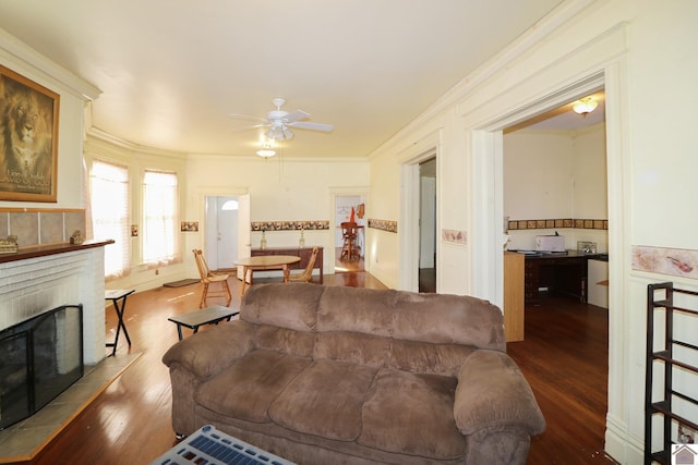 living room featuring ceiling fan, wood-type flooring, crown molding, and a fireplace