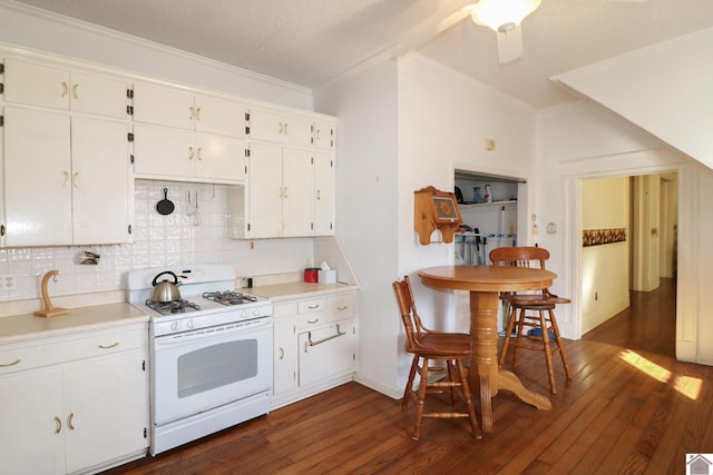 kitchen featuring gas range gas stove, white cabinetry, dark hardwood / wood-style flooring, tasteful backsplash, and ceiling fan