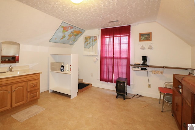 interior space with vaulted ceiling, sink, and a textured ceiling