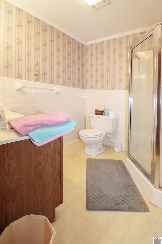 bathroom featuring vanity, tile walls, toilet, a shower with shower door, and crown molding