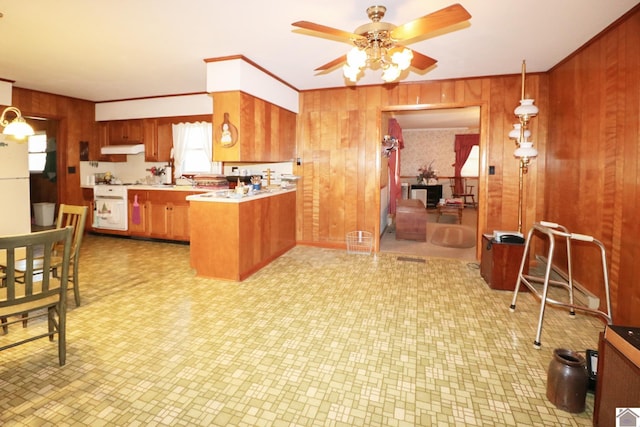 kitchen featuring ceiling fan, hanging light fixtures, kitchen peninsula, and wooden walls