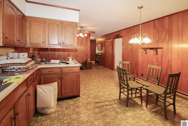 kitchen featuring ceiling fan with notable chandelier, wood walls, and decorative light fixtures