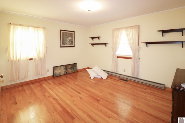 interior space featuring light hardwood / wood-style floors, a baseboard heating unit, and crown molding