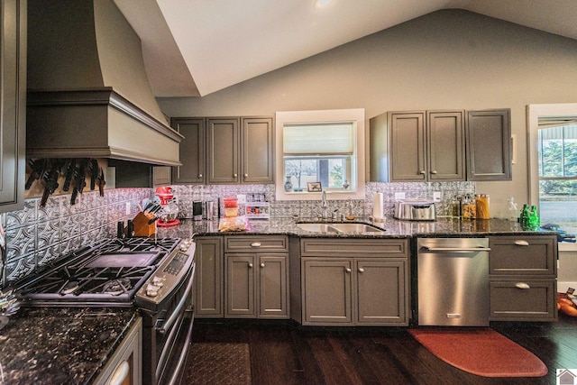 kitchen featuring stainless steel gas stove, custom range hood, sink, dark stone counters, and lofted ceiling