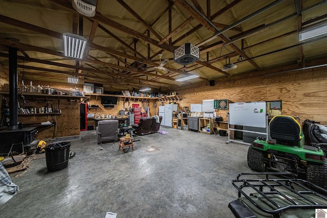 garage with a wood stove, a workshop area, a garage door opener, and wooden walls